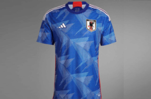 JAPÃO (Adidas) - UNIFORME 1 - Predominantemente azul, a camisa da seleção japonesa conta com alguns desenhos em branco e uma listra vermelha na lateral. Além disso, a numeração na peça será em dourado