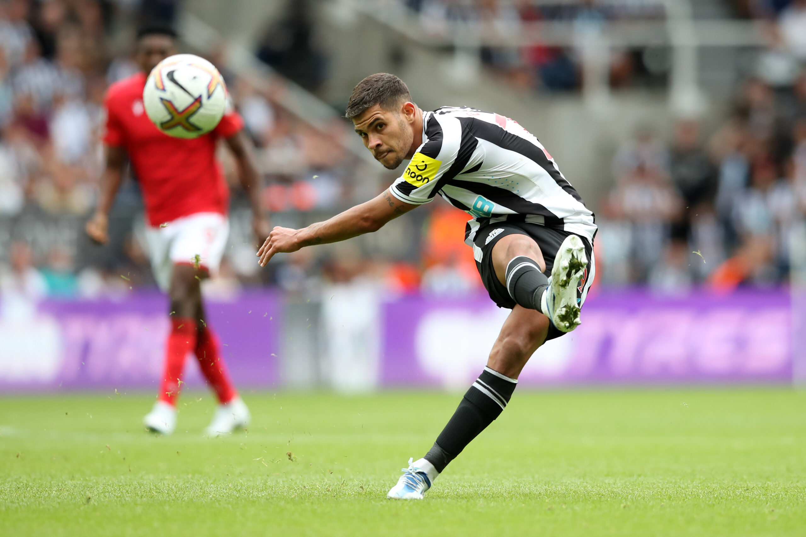  Bruno Guimaraes in action during a match between Newcastle United and Nottingham Forest, with the backdrop of the stadium stands.